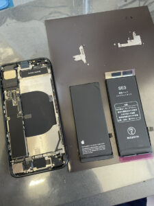 iPhone SE3のバッテリー交換作業中の本体と、取り外したバッテリー・交換用バッテリー