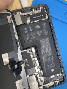 iPhone XSの画面パネルを取り外し、内部のバッテリーや基板が露出している修理作業中の状態。