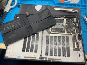 発火のリスクに注意しながら、本体に強力に接着された古いバッテリーを慎重に取り外した状態