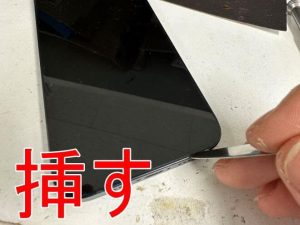 画面と本体フレームのとの間にヘラを挿したiPhone13