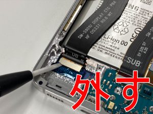 画面パーツコネクタに接続されたケーブルを外した画面交換修理中のGalaxy S22