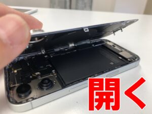 背面パネルを剥がして持ち上げているドックコネクター交換修理中のiPhone16