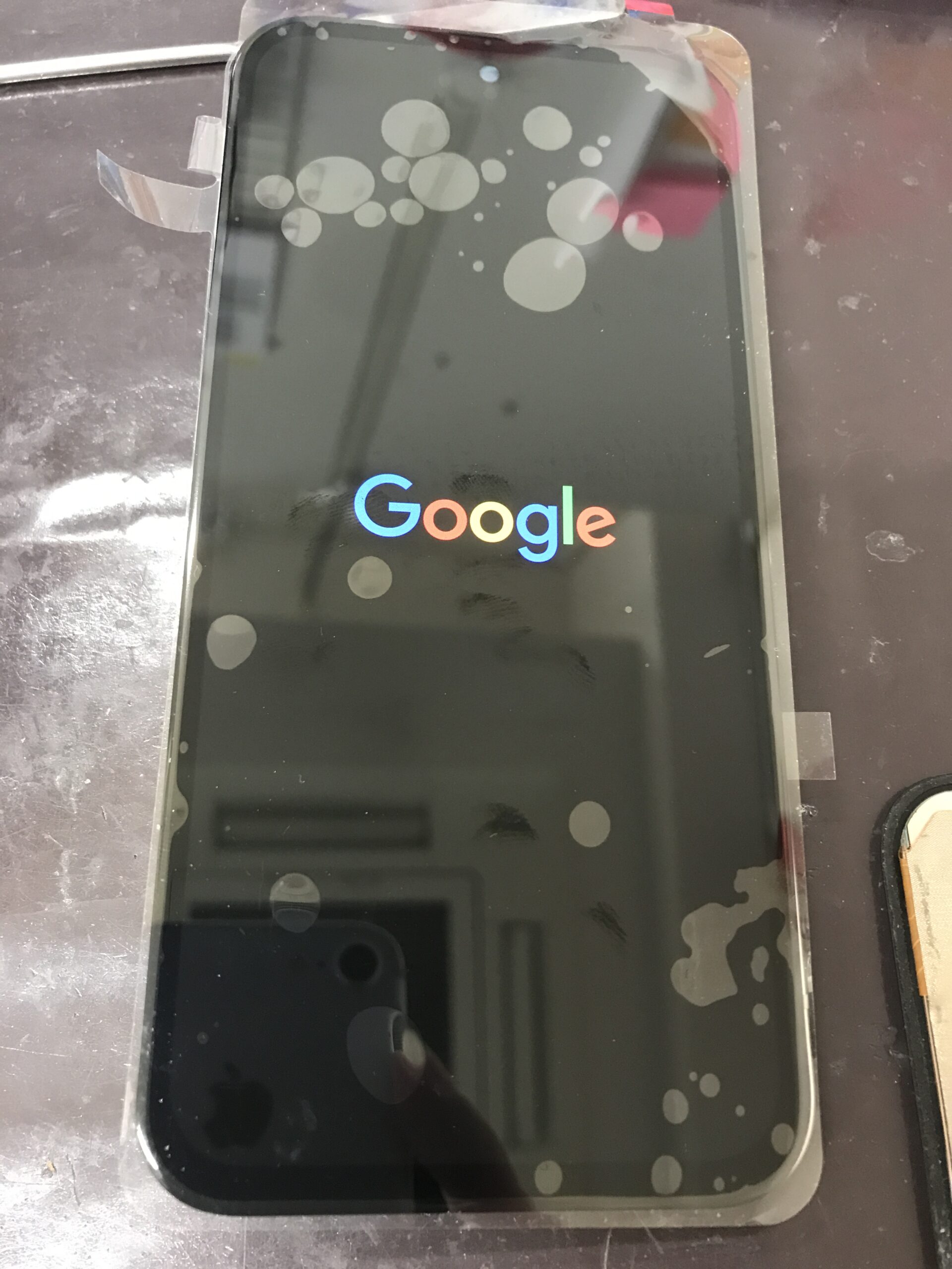 Google Pixel 8aの画面交換修理中に新パーツを仮付けして起動確認している状態
