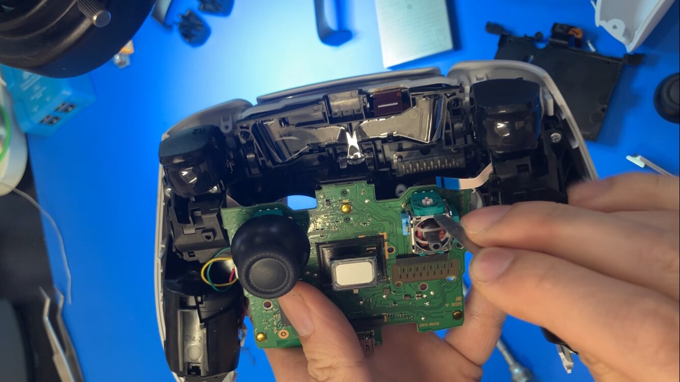 DualSenseのポテンショメータにヘラを差し込んで開く様子