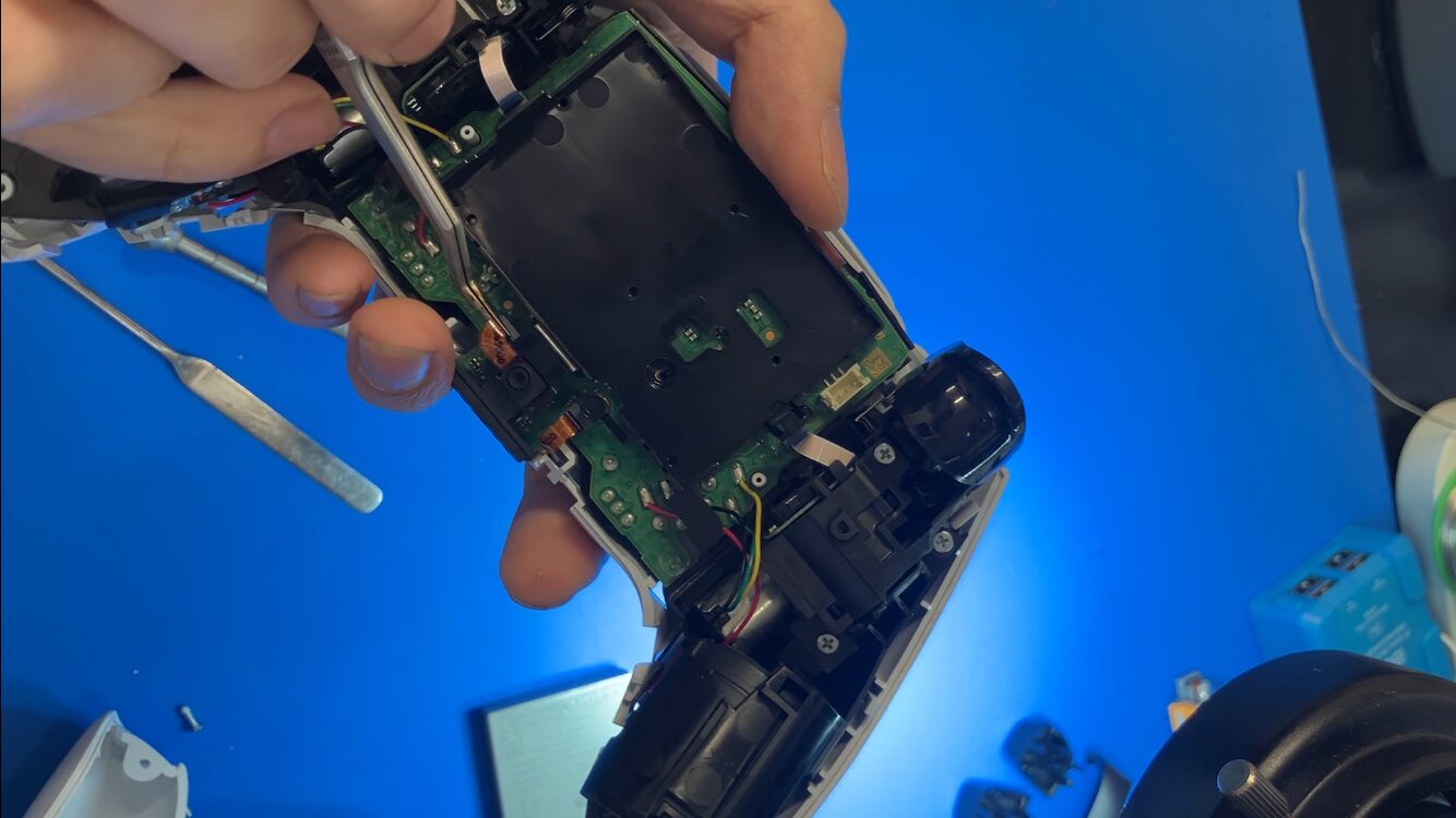 DualSenseのバッテリー固定カバーに接続されたコネクターを取り外す様子