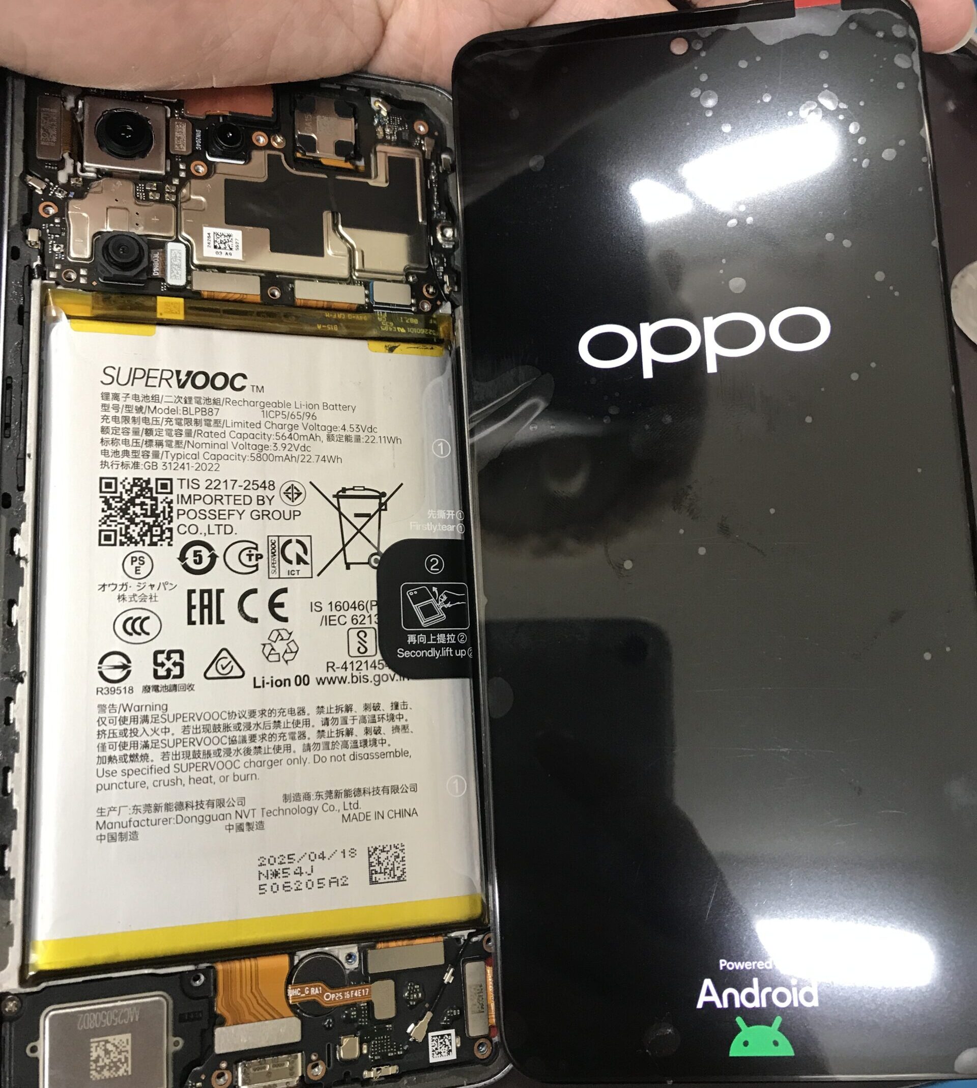 OPPO Reno13 Aに交換用画面パネルを仮付けして映像表示を確認している修理中の状態