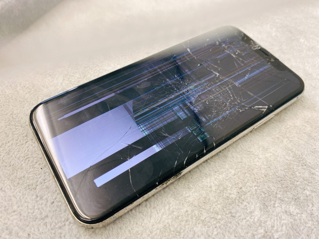 強い衝撃を受けて、ガラス我だけでなく液晶まで破損し表示が乱れているiPhone XS